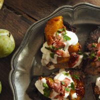 Greengage plum, bacon, and burrata crostini on a plate with apples on the side